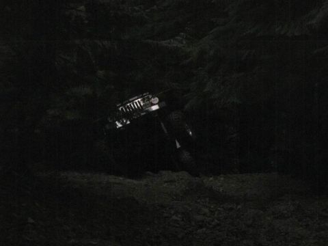 1985 Ford Bronco - A dark, off-road vehicle, possibly a Jeep Wrangler, navigates a steep, rocky incline at night. The vehicle's headlights illuminate the roug…