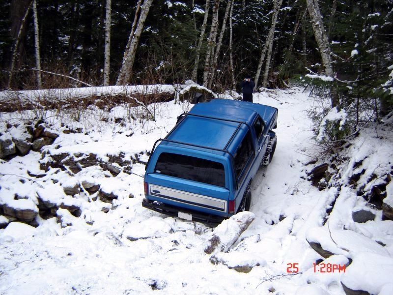 Blue Ford Bronco on a snowy forest trail.