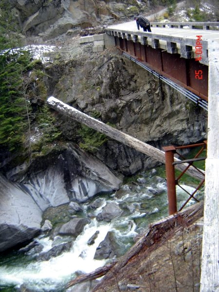 1985 Ford Bronco - A bear walks across a bridge over a rocky river. The scene is set in a mountainous, wooded area with snow on the ground.