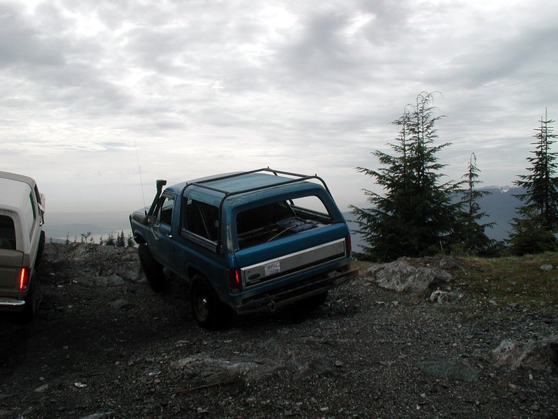 1985 Ford Bronco parked on a rocky mountain overlook.