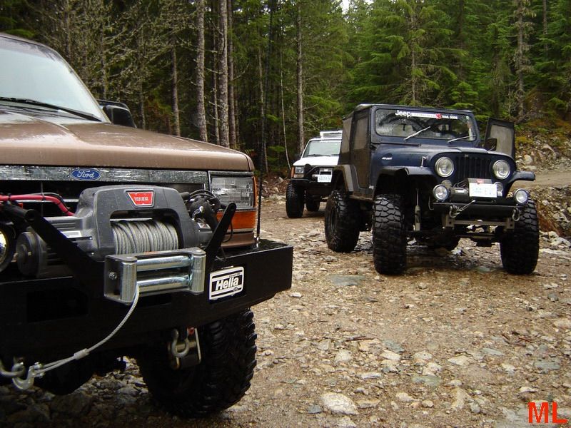 Off-road vehicles including a Ford Bronco and a Jeep on a forest trail.