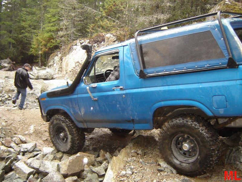 Blue Ford Bronco with snorkel on a rocky trail, person walking behind.