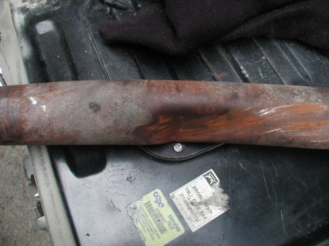 1985 Ford Bronco - A close-up, horizontal shot shows a rusty metal pipe with some white paint streaks and a dent. Below the pipe, there are two stickers on a…