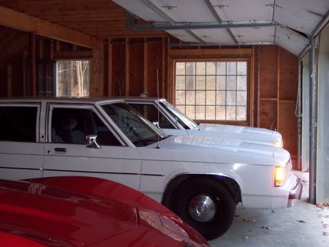 2001 Ford Crown Victoria - A white 2001 Ford Crown Victoria is parked inside a garage next to another vehicle.