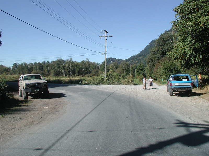 Two Ford Bronco SUVs parked on a gravel road with people nearby.