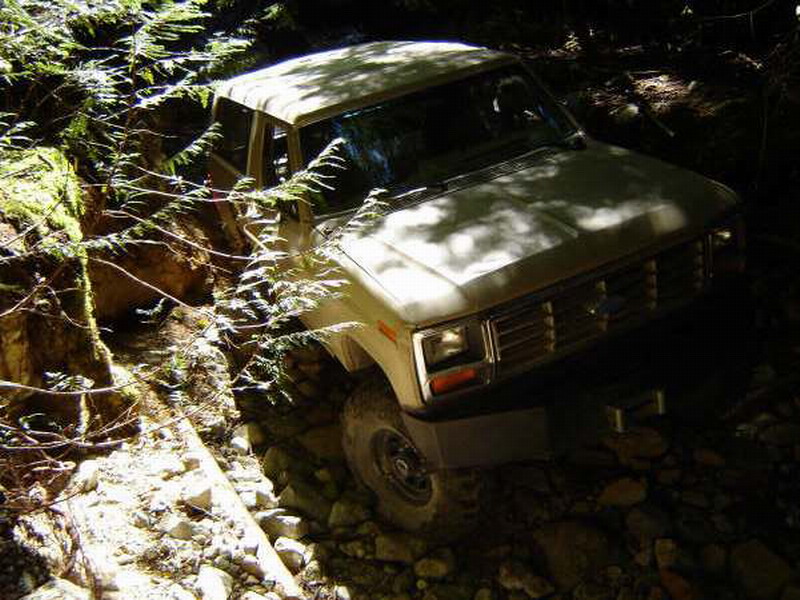 1980s SUV driving on a rocky, wooded trail.