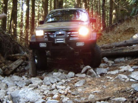 1985 Ford Bronco on a rocky forest trail, front view.