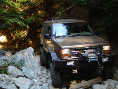 Brown Ford Explorer off-roading on a rocky trail with a winch.