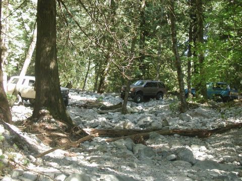Off-road vehicles on a rocky trail in a forest.