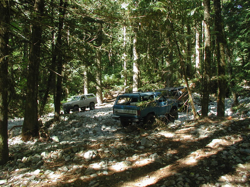 Off-road vehicles on a rocky trail in a forest.