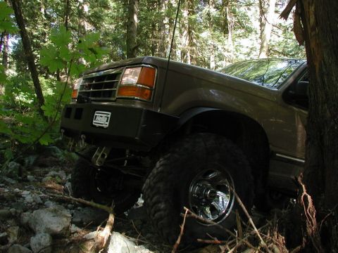 Lifted brown SUV on a rocky trail with a Hella bumper.