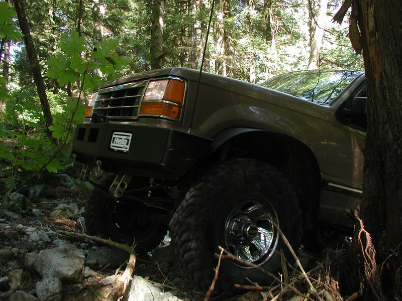 Lifted brown SUV on a rocky trail with a Hella bumper.