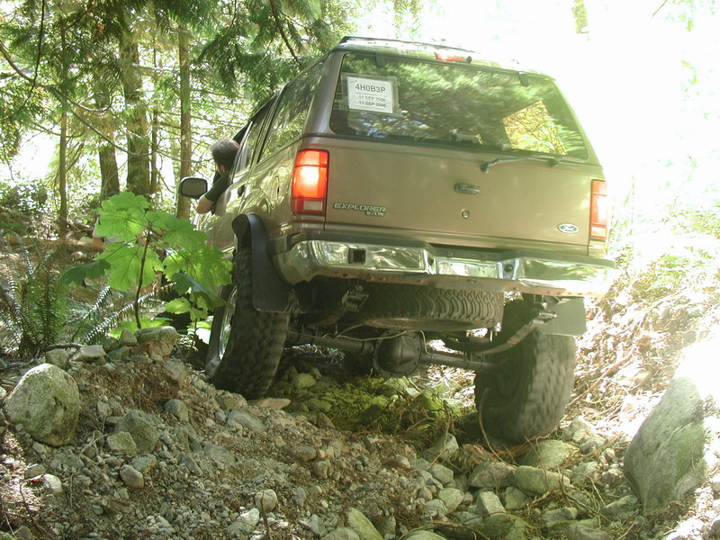 Tan Ford Explorer off-roading on a rocky trail, tilted to the right.