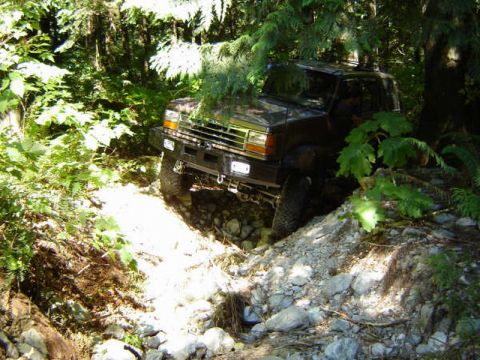 Dark SUV on a rocky, wooded trail.