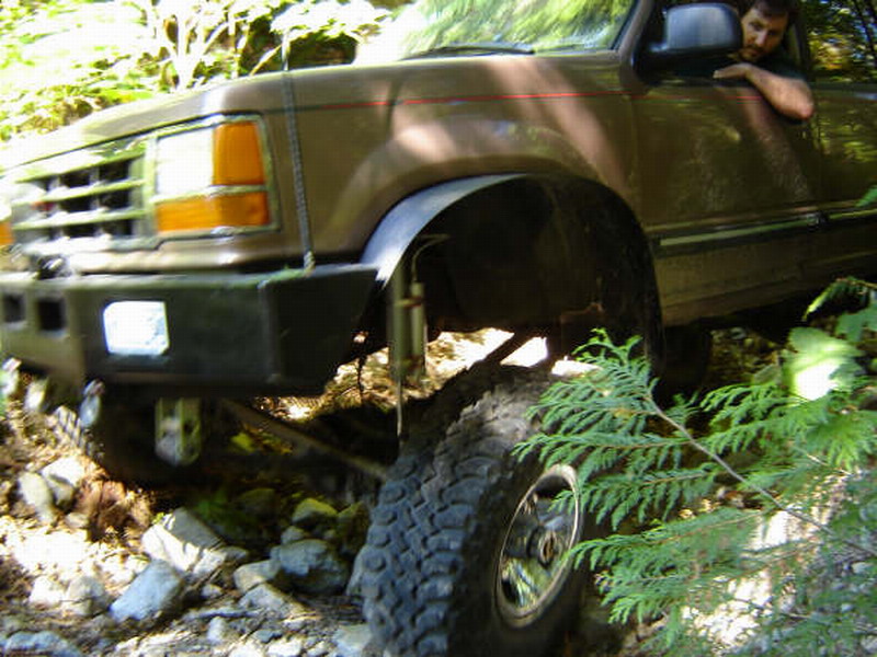 Brown Ford Bronco on a rocky trail with large off-road tires.