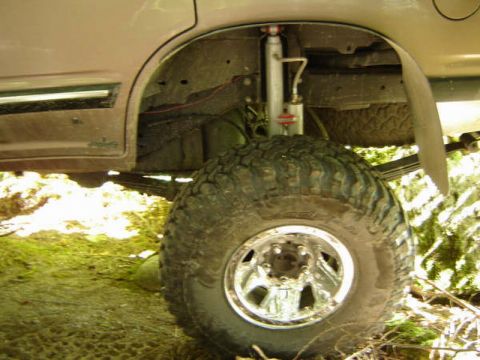 Lifted off-road vehicle rear wheel well with large tire, shock, and leaf springs.