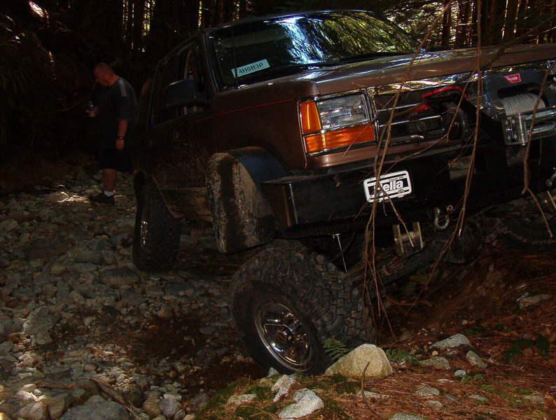 Brown Ford Bronco on a rocky trail in a forest.