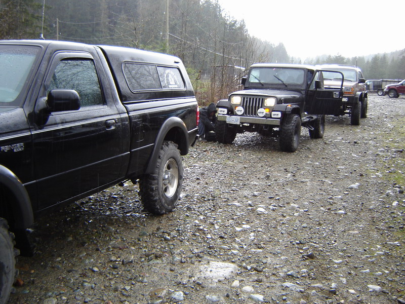 Black Ford Ranger pickup truck and Jeep Wranglers on a gravel road.