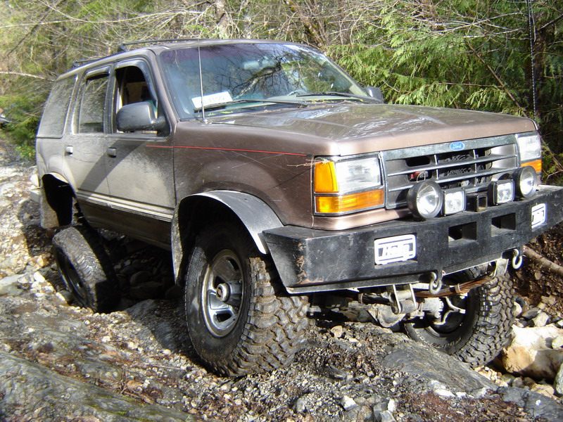 Brown Ford Explorer off-roading on a rocky trail.