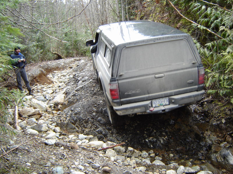 Pickup truck with camper shell on a rocky off-road trail.