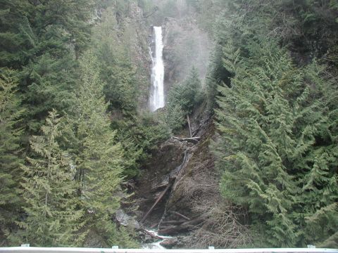 1985 Ford Bronco - A tall waterfall cascades down a rocky, tree-lined mountainside.