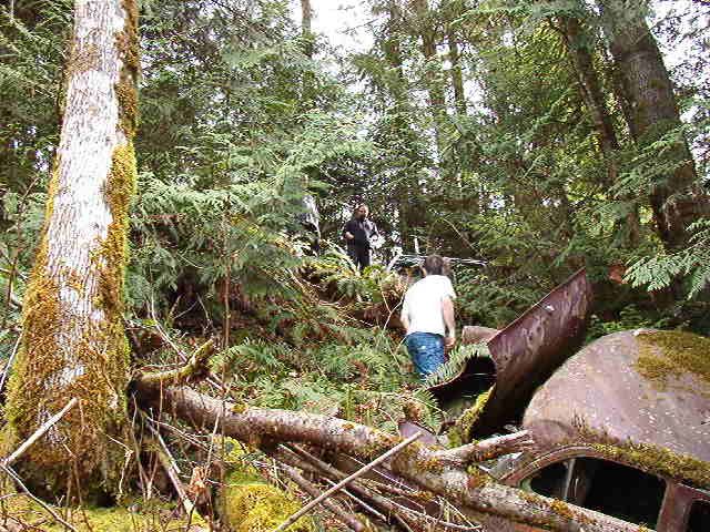 Rusty vehicle in forest with two people in background