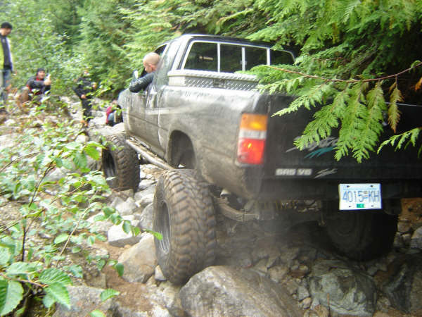 Off-road pickup truck with large tires driving on a rocky trail.