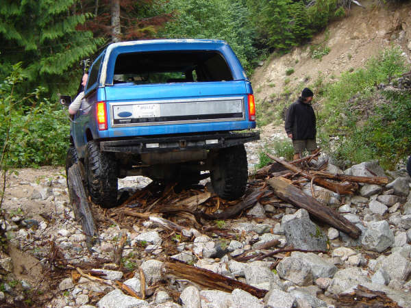 Blue Ford Bronco on a rocky trail with a person watching.
