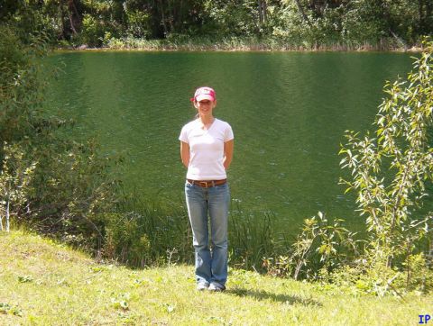 1985 Ford Bronco - A woman stands in front of a green lake with trees in the background.