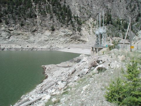 1985 Ford Bronco - A wide shot of a reservoir next to a steep, rocky mountainside with a hydroelectric power station visible on the right.