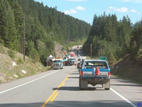 Blue Ford pickup truck with red gas cans on tailgate driving on a highway.
