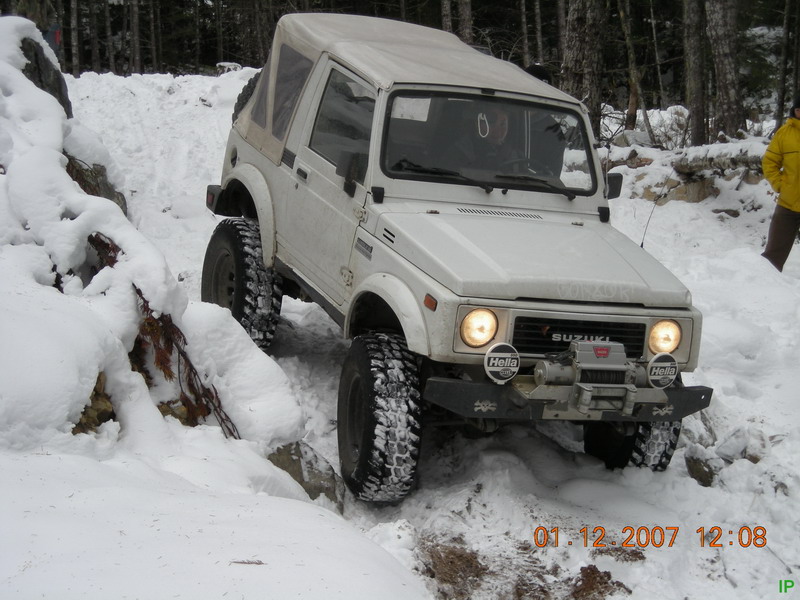 White Suzuki Samurai off-roading in snow with winch and Hella lights
