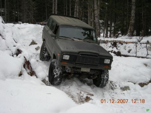 Dark four-door SUV with large tires on a snowy trail.