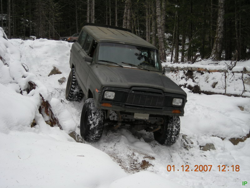 Dark four-door SUV with large tires on a snowy trail.