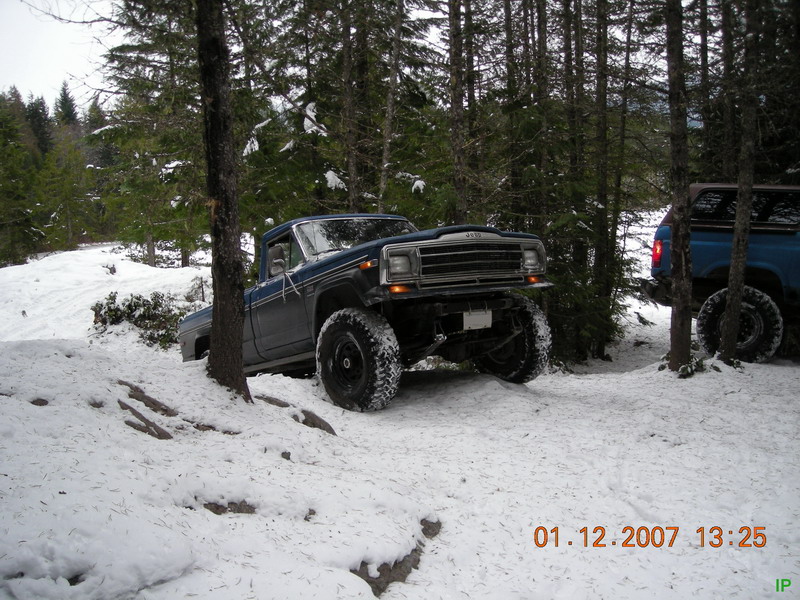 Lifted Jeep pickup truck in a snowy forest setting.