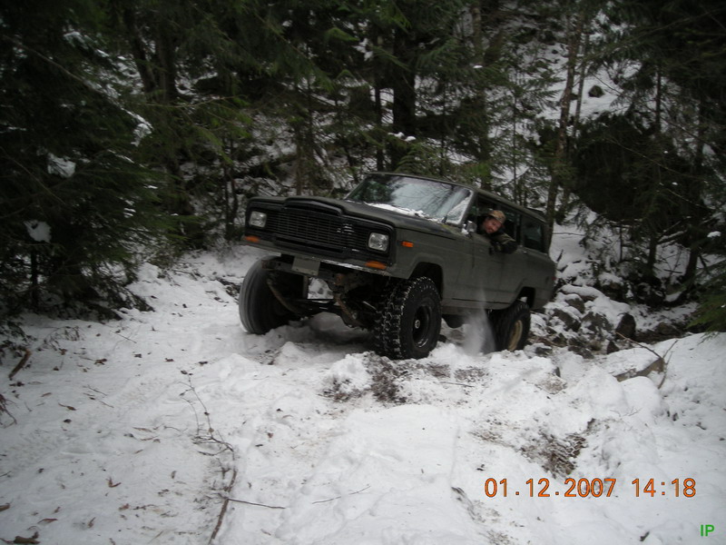 Dark SUV driving on a snowy wooded trail.