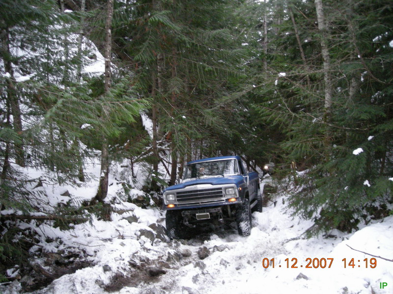 Blue 1980s Ford pickup truck on a snowy, wooded trail.