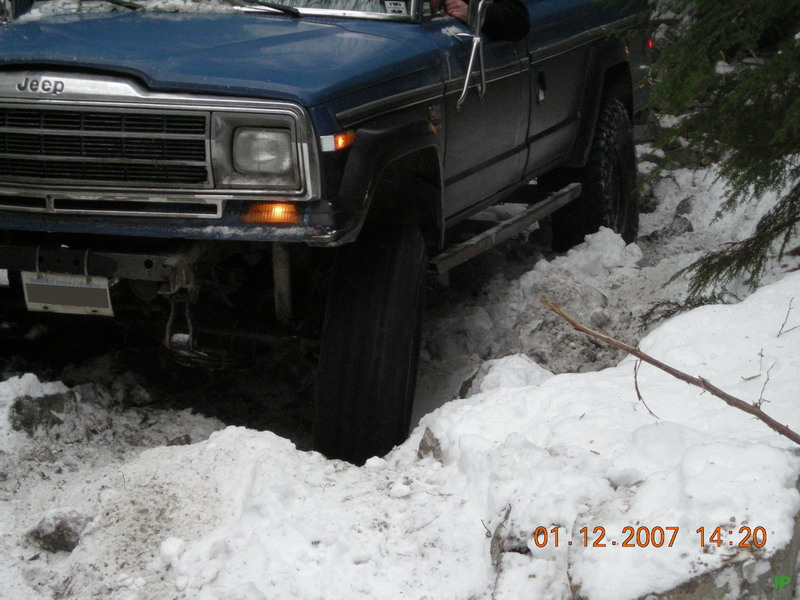 Blue Jeep SUV on a snowy off-road trail, front view.