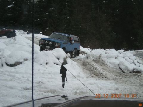 Blue 1980s SUV driving on a snowy trail.