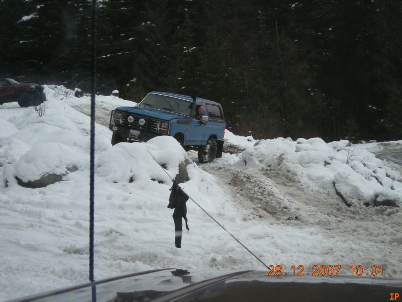 Blue 1980s SUV driving on a snowy trail.