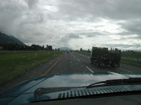 View from inside a vehicle driving on a wet highway with a truck ahead.