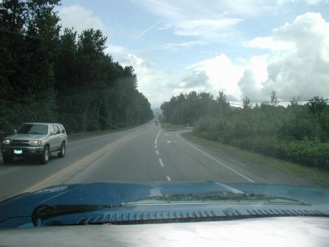 Silver SUV driving on a road with trees on the side.