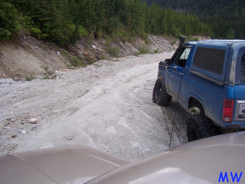 Blue 1980s Ford Bronco with snorkel on a gravel road.