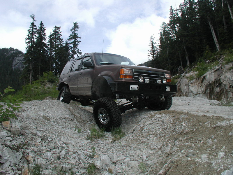 Lifted dark brown Ford Explorer on a rocky off-road trail.