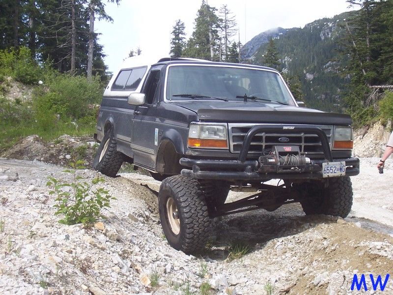 Lifted Ford Bronco with winch on a rocky off-road trail.