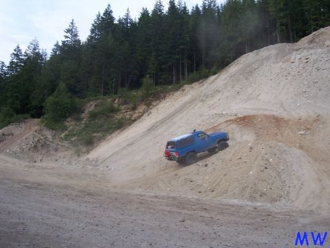 Blue Ford Bronco climbing a steep sandy hill