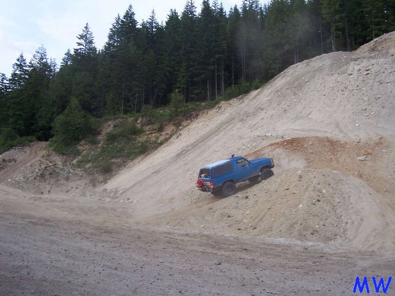 Blue Ford Bronco climbing a steep sandy hill