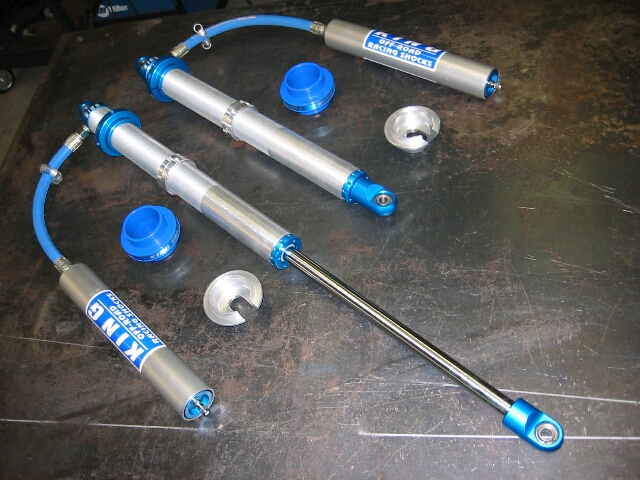 Pair of King off-road racing shocks with blue end caps on a workbench