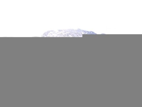 Snow-covered mountain range under a bright, overcast sky.
