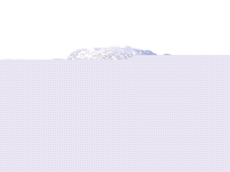 Snow-covered mountain range under a bright, overcast sky.